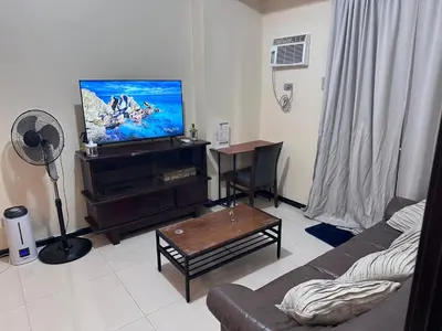 a living room with a couch and a flat screen tv at Affordable 1BR Condo In Pasay with Balcony and Amenity View, Free Pool Fast WiFi Near NAIA Airport , MOA,PICC in Manila