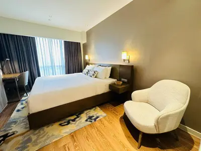 a hotel room with a bed and a chair at Hotel Residence Acqua - Novotel Suites in Manila