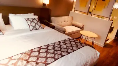 a hotel room with a bed and a chair at Hotel Residence Acqua - Novotel Suites in Manila