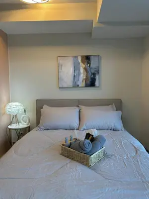 a bed with a basket of towels on it at 35th Prime Staycation BGC in Manila