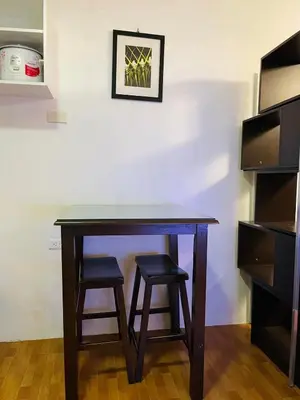 a wooden table with two stools in a room at Cozy Transient Home Uno in Manila