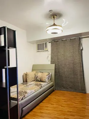 a living room with a bed and a window at Cozy Transient Home Uno in Manila