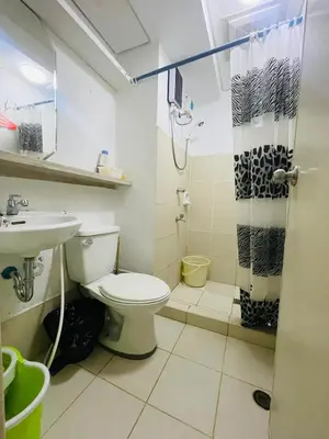 a bathroom with a toilet and a shower and a sink at Cozy Transient Home Uno in Manila
