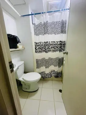 a bathroom with a toilet and a shower curtain at Cozy Transient Home Uno in Manila