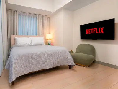 a hotel room with a bed and a chair at Modern 2-Bedroom BGC Condo by Uptown Mall in Manila