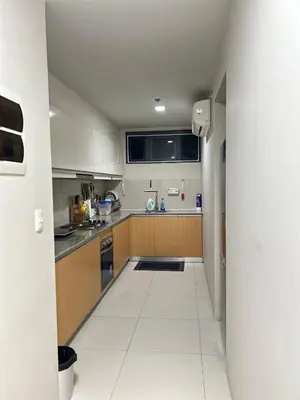 a large kitchen with white tile floor and wooden cabinets at Condotels by ZJM Residence in Manila