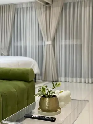 a living room with a green couch and a table with a plant at Uptown Parksuites Balcony Mall View in Manila