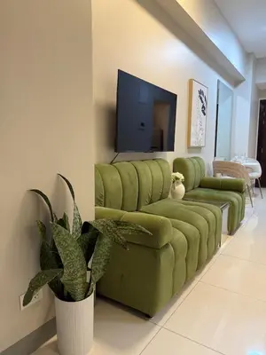 a living room with a green couch and a tv at Uptown Parksuites Balcony Mall View in Manila