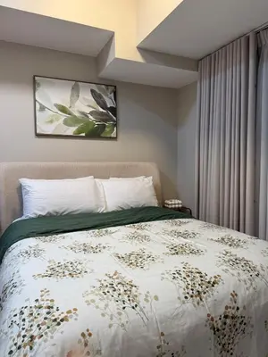 a bedroom with a bed with a green and white comforter at Uptown Parksuites Balcony Mall View in Manila