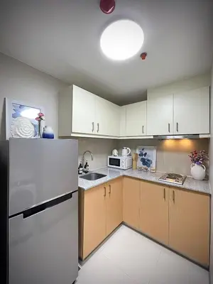 a kitchen with white cabinets and a white refrigerator at Uptown Parksuites Balcony Mall View in Manila