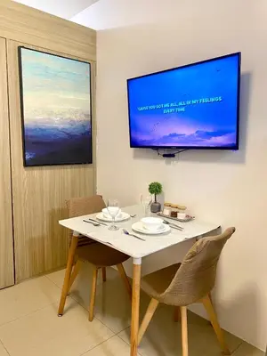 a dining room table with chairs and a tv on the wall at Shore Residences Tower B in Manila