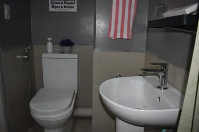 a bathroom with a white toilet and a sink at The Cube at 15th in Taytay