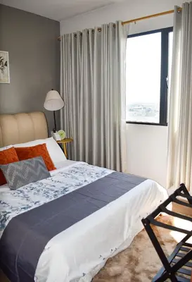 a bedroom with a bed and a large window at The Cube at 15th in Taytay