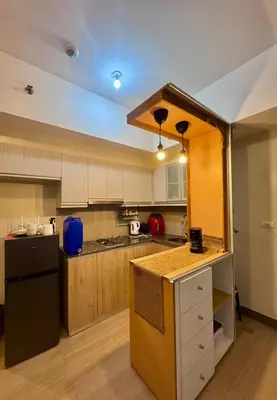 a kitchen with wooden cabinets and a black refrigerator at Cozy Studio at Venice Grand Canal Near BGC & NAIA in Manila