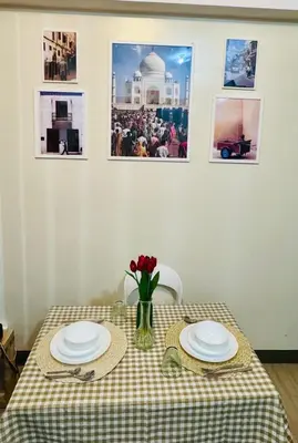 a table with two plates and a vase of flowers on it at Cozy Studio at Venice Grand Canal Near BGC & NAIA in Manila