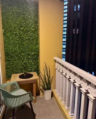 a balcony with a green wall and a chair at Cozy Studio at Venice Grand Canal Near BGC & NAIA in Manila