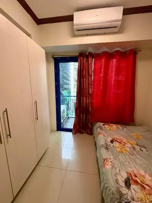a bedroom with a bed with a red curtain and a window at Melas Condotel in Manila