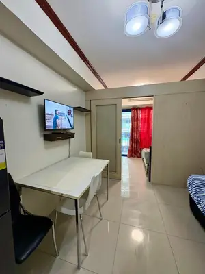 a living room with a table and a tv on the wall at Melas Condotel in Manila