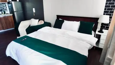 a bedroom with a large bed with green and white sheets at Reset at the Gramercy in Manila
