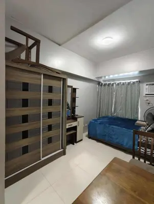 a bedroom with a bed and a dresser and a desk at Staycation by Carlo and Chel's in Manila