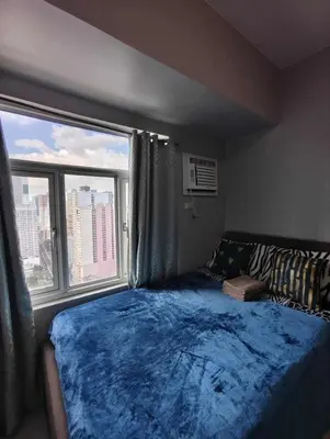 a bedroom with a bed and a large window at Staycation by Carlo and Chel's in Manila