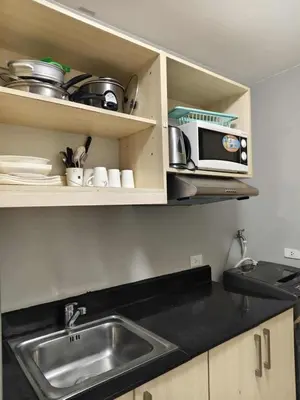 a kitchen with a sink and a microwave at Staycation by Carlo and Chel's in Manila