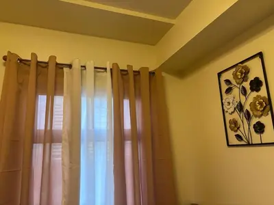 a room with a window with curtains and a picture at Cozy Staycation in Cubao with Netflix in Manila