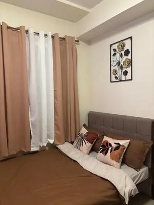 a couch in a room with curtains and pillows at Cozy Staycation in Cubao with Netflix in Manila