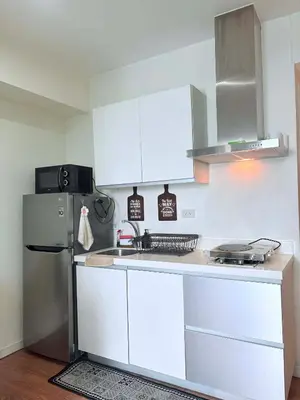 a kitchen with white cabinets and a refrigerator at 1 bedroom at Azure Urban Resort Condo in Manila