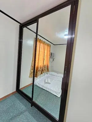 a bedroom with a bed through a mirror at Cozy Bian Getaway - Entire House for Rent in Biñan