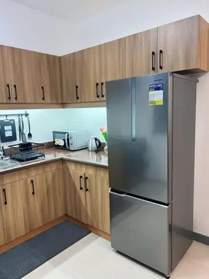 a stainless steel refrigerator in a kitchen with wooden cabinets at Raya and Zane in Manila
