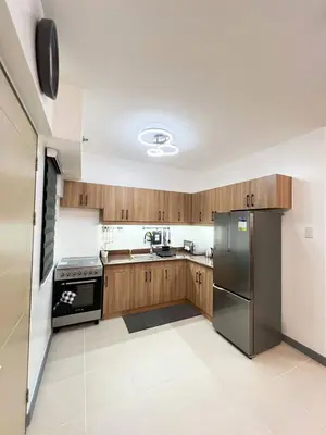 a kitchen with wooden cabinets and a stainless steel refrigerator at Raya and Zane in Manila