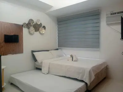 a bedroom with two beds and a window with a fan at Cozy Condo Near US Embassy in Manila in Manila