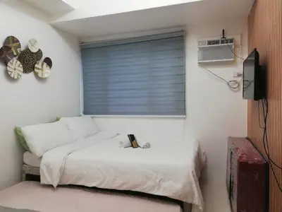 a bedroom with a white bed and a window at Cozy Condo Near US Embassy in Manila in Manila