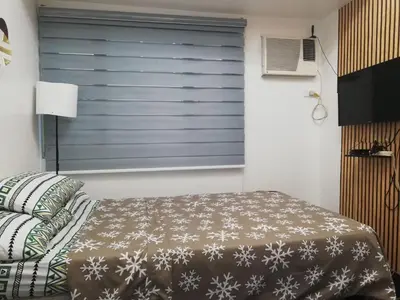 a bedroom with a bed and a window with snow flakes at Cozy Condo Near US Embassy in Manila in Manila