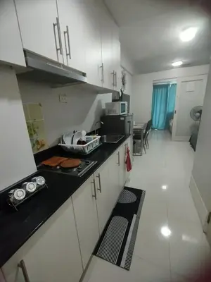 a kitchen with white cabinets and a black counter top at Sea Residences Near MOA SMX Pasay City in Manila