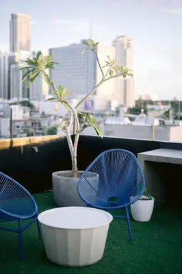 three chairs and a potted plant on a balcony at Canopy Agutaya BGC in Manila