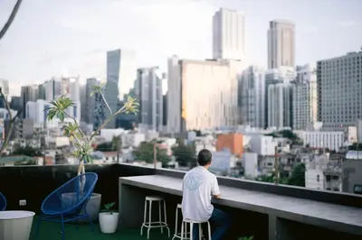 a man sitting at a table on a balcony overlooking a city at Canopy Agutaya BGC in Manila