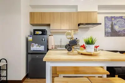 a kitchen with a wooden counter top and a refrigerator at Stylish Condo - Cozy Urban Living in Manila