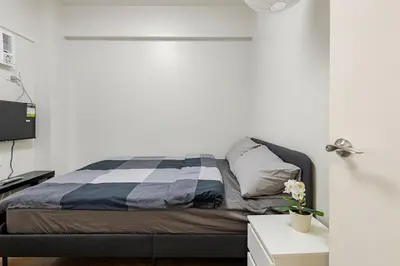 a bedroom with a bed and a desk and a tv at Stylish Condo - Cozy Urban Living in Manila