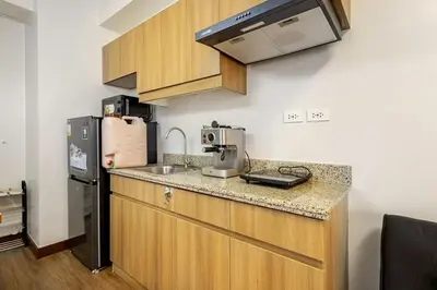 a kitchen with a sink and a refrigerator at Stylish Condo - Cozy Urban Living in Manila