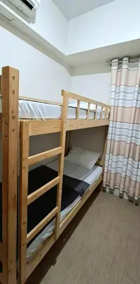 two bunk beds in a room with a curtain at Cozy Modern 2 Bedroom 81 Newport Boulevard in Manila