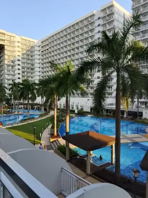 a view from the balcony of a hotel with a pool and palm trees at Josh place Shell residence MOA in Manila