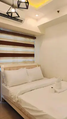 a bedroom with a bed with a wooden headboard at Josh place Shell residence MOA in Manila