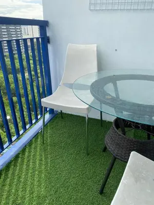 a glass table and a white chair on a balcony at Moa Staycaion Stern Homes in Manila