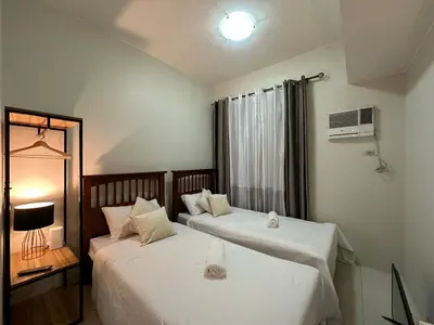 two beds in a hotel room with a window at Prime Salcedo Square Studio 2 Beds in Manila