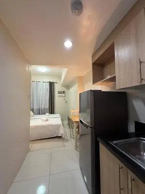 a kitchen with a black refrigerator and a bed at Prime Salcedo Square Studio 2 Beds in Manila