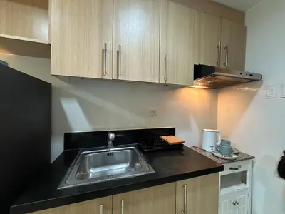 a kitchen with a sink and wooden cabinets at Prime Salcedo Square Studio 2 Beds in Manila