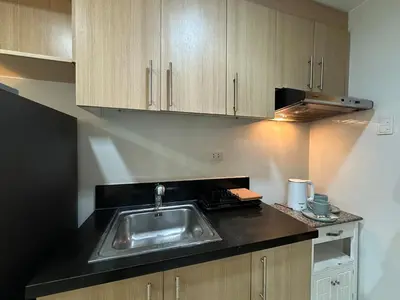 a kitchen with a sink and wooden cabinets at Prime Salcedo Square Studio 2 Beds in Manila