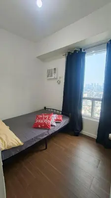 a bedroom with a bed with blue curtains and a window at 2 Bedroom MEZZA RESIDENCES in Manila